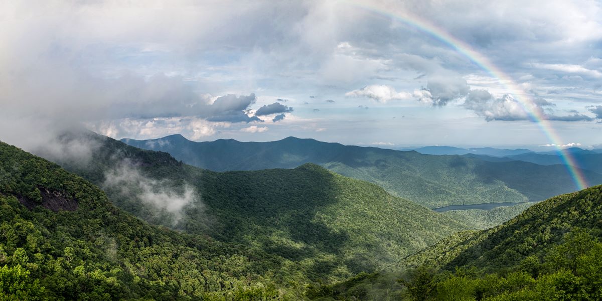 Rainbow over tree covered mountains.